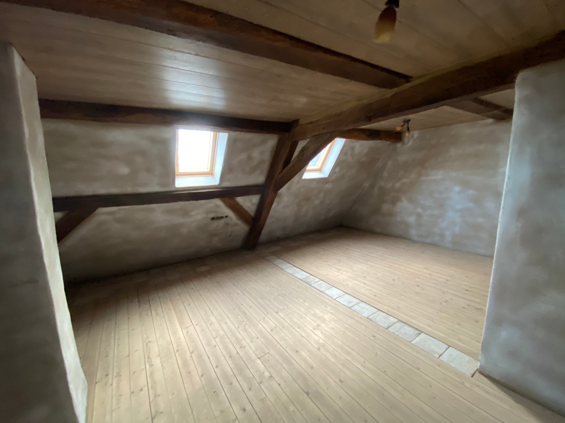 Ausgebautes Dachgeschoss mit hellen Holzdielen und verputzten Wänden